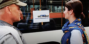 Frau und Mann stehen vor einem Bus und schauen auf eine Muster-Buswerbung